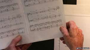 A member of a funeral choir holding sheet music